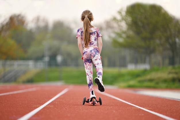 Een klein meisje met scooter op een stadion