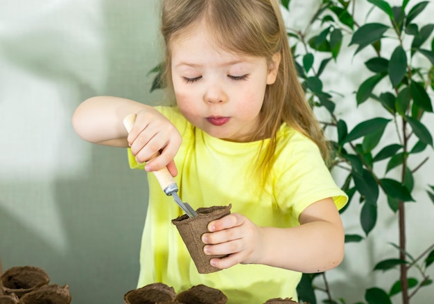 Een klein meisje plant zaden in een pot Concept van tuinieren