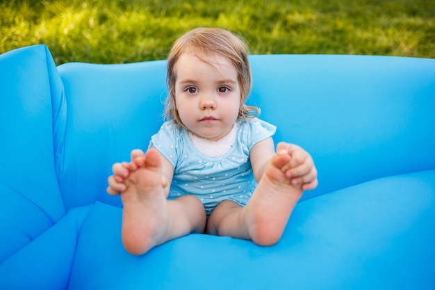 een klein meisje rust en speelt in de frisse lucht. rotzooien op een blauwe opblaasbare matras