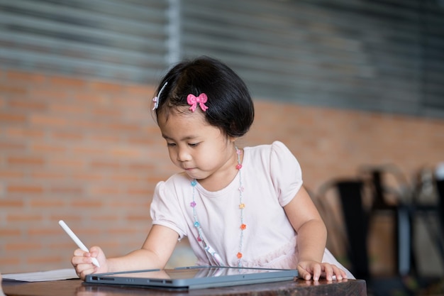 Een klein meisje schrijft op een tablet