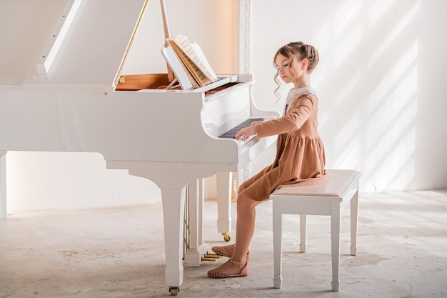 Een klein meisje speelt een grote witte piano in een heldere, zonnige kamer