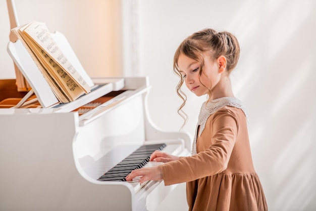 Een klein meisje speelt een grote witte piano in een heldere, zonnige kamer