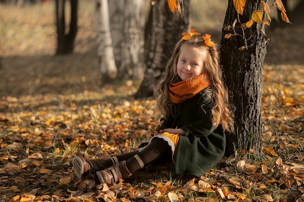 Een klein meisje speelt met bladeren in een herfstpark