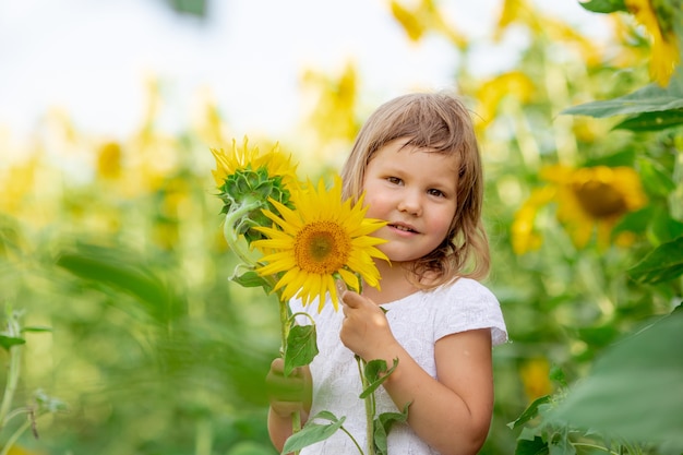 Een klein meisje speelt met zonnebloembloemen in een veld met zonnebloemen