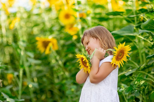 Een klein meisje speelt met zonnebloembloemen in een veld met zonnebloemen