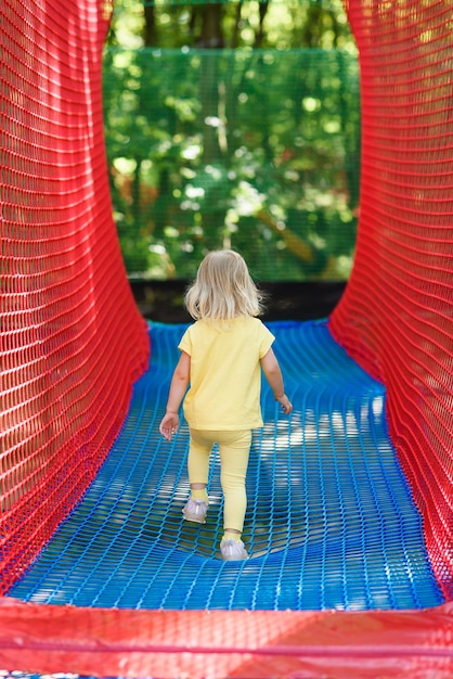 Een klein meisje speelt op een speeltuin met touwen. Het meisje speelt op nettouwen.