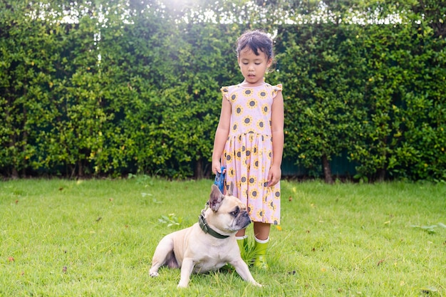 Een klein meisje staat in het gras met een hond.