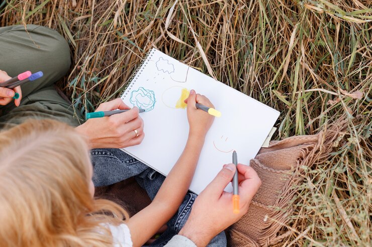 Een klein meisje tekent met haar ouders tijdens een picknick. detailopname