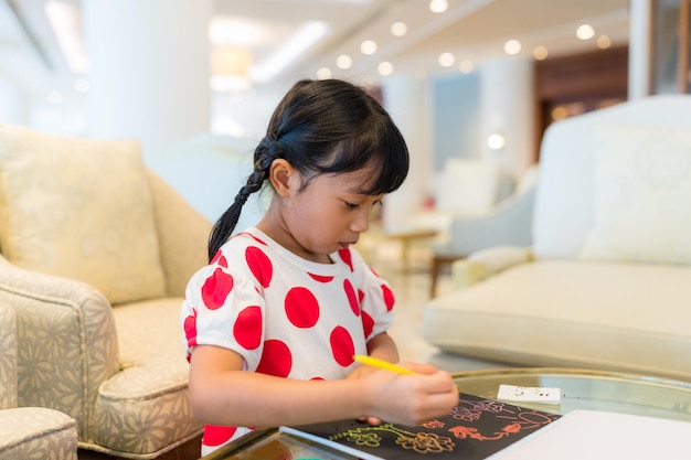 Een klein meisje tekent op een boek.