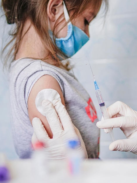 Een klein meisje toont haar schouder aan de dokter vaccinatie in de schouder Massale vaccinatie en immunisatie van de bevolking