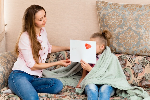 Een klein meisje trekt een wenskaart voor moeder op moederdag met de woorden 
