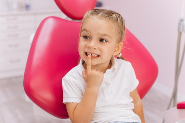 Een klein meisje wijst naar een tand die haar zorgen baart voor de tandarts