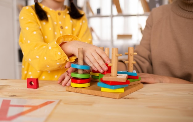 Een klein meisje zit aan een tafel en speelt een zich ontwikkelend houten speelgoed Ontwikkeling van het kind