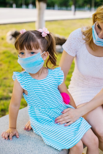 Een klein meisje zit in een medisch masker in de open luchtBescherming tegen virussen en allergenen