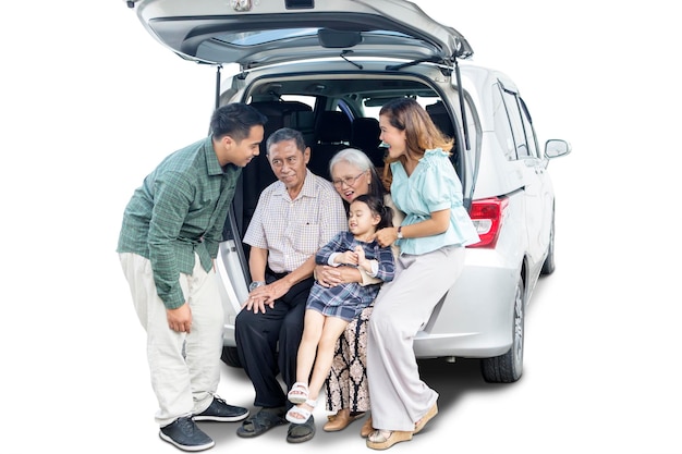 Een klein meisje zit met haar grote familie in de kofferbak van de auto.