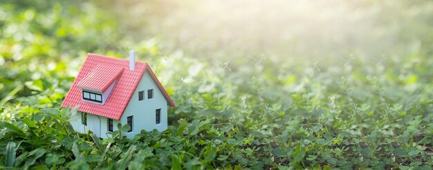 Foto een klein model van een modern huis dat op het grasveld is geplaatst huishandelsconcept en levensconcept eco-vriendelijk huis met zonlicht abstracte achtergrond