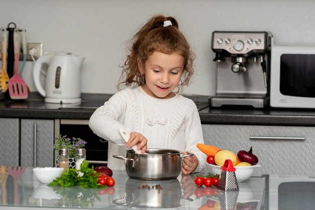 Een klein mooi meisje kookt in de keuken van verse groenten. Conceptuele fotografie.