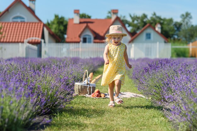 Een klein mooi meisje loopt door het brede paarse veld van lavendel.