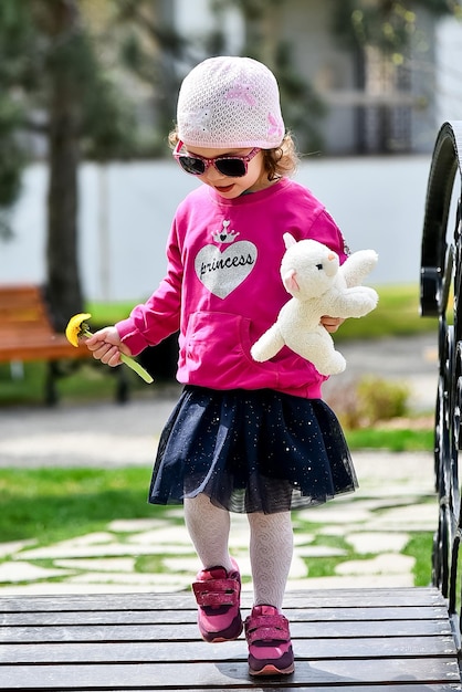 Een klein schattig meisje in een roze jasje en roze hoed loopt door de stad Lente Zonnig Gelukkige jeugd