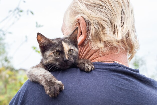 Foto een klein zwart katje op de schouder van een man. favoriete huisdieren.