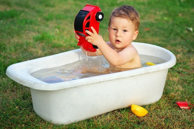 Een kleine baby baadde in het bad en speelde met speelgoedauto.