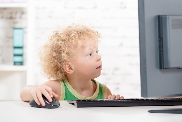 Een kleine blonde jongen die met computer speelt