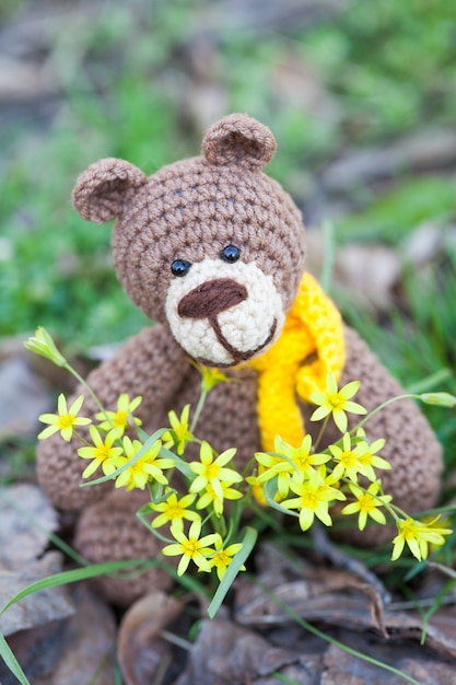Een kleine bruine beer met een gele sjaal. Gebreide speelgoed, handgemaakte, amigurumi