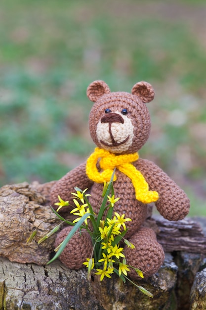 Een kleine bruine beer met een gele sjaal. Gebreide speelgoed, handgemaakte, amigurumi