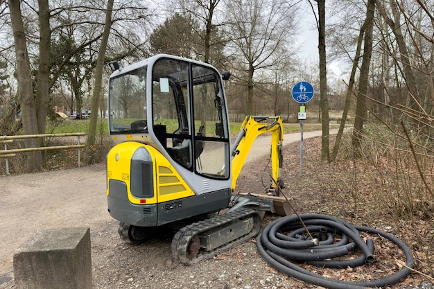 Een kleine gele crawler tractor in een park in het vroege voorjaar bij het voetgangerspad