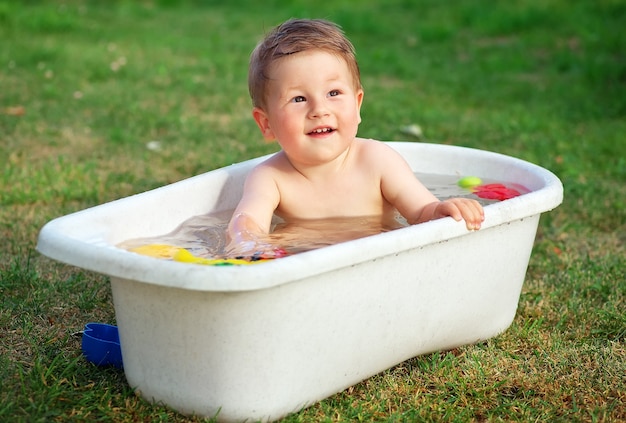 Een kleine gelukkige baby baadde in het bad en speelde in een bad met speelgoed.