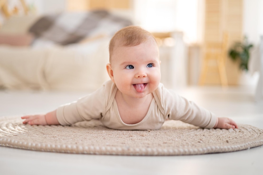 Als Je Naar Me Kijkt Een kleine gezonde baby in een katoenen bodysuit ligt op zijn buik op