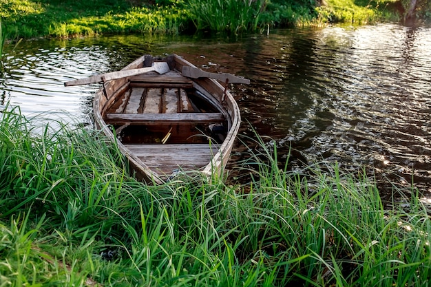 Foto een kleine houten roeiboot met een gebroken bodem op een kalm meer dichtbij de kust.