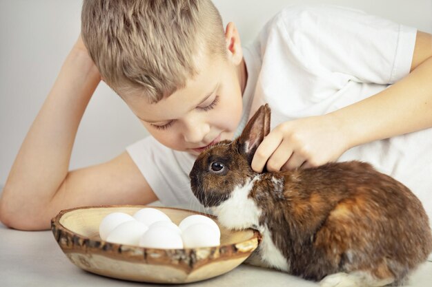 Een kleine jongen aait de paashaas, de witte eieren zijn vlakbij