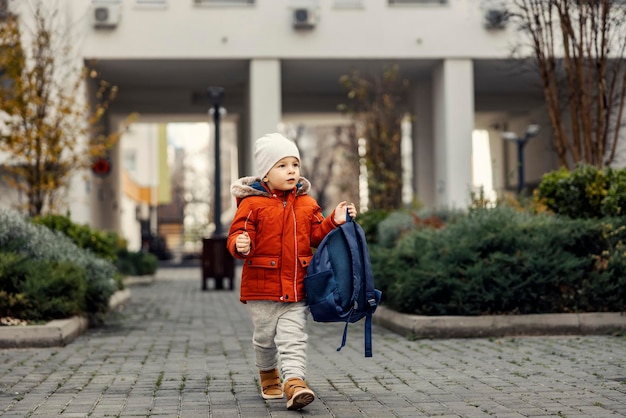 Een kleine jongen die een schooltas draagt en op de eerste dag terugkeert van de kleuterschool