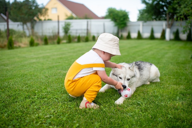 Een kleine jongen die met de hond in de tuin speelt