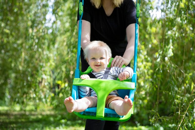 Een kleine jongen die plezier heeft met spelen op een schommel onder een boom in een tuin