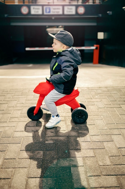 Een kleine jongen die plezier heeft met zijn voertuig op straat