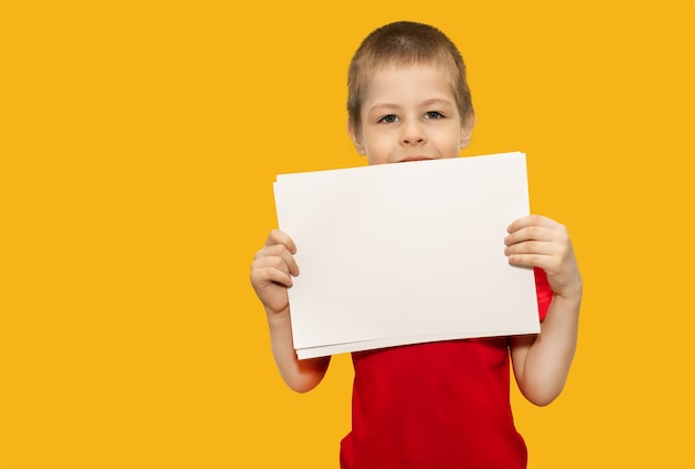 Een kleine jongen houdt een papier vast op een gele achtergrond