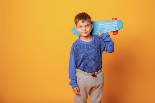 Een kleine jongen houdt een skate vast op een gele achtergrond