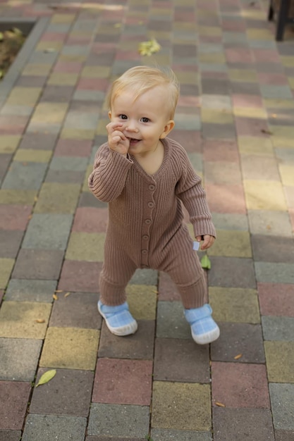 een kleine jongen in een bruine jumpsuit loopt vrolijk door het park