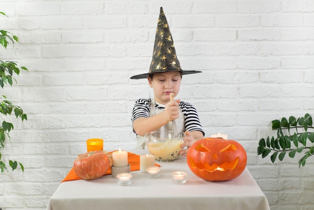 Een kleine jongen in een Halloween-kostuum kookt cupcakes voor het feest