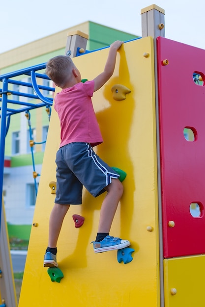 Een kleine jongen in een rood t-shirt op de speelplaats