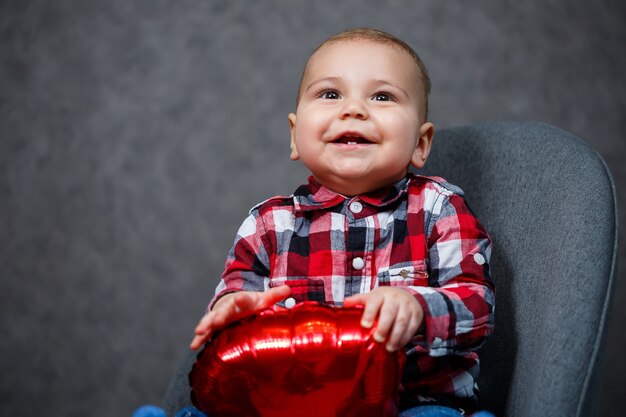 Een kleine jongen in een shirt speelt met een ballon in de vorm van een hart