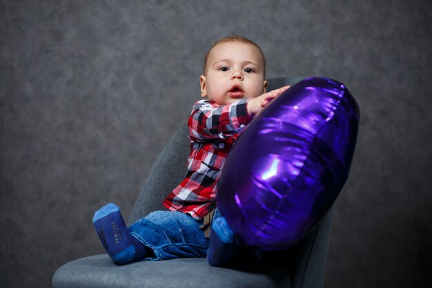 Een kleine jongen in een shirt speelt met een ballon in de vorm van een hart