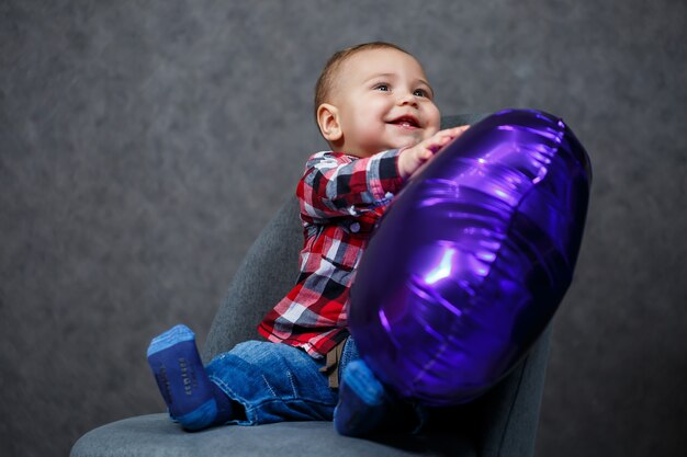 Een kleine jongen in een shirt speelt met een ballon in de vorm van een hart