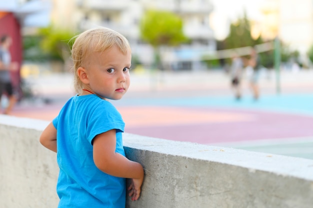 Een kleine jongen kijkt tieners spelen met een bal