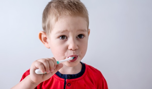Een kleine jongen leert zijn tanden te poetsen met een tandenborstel