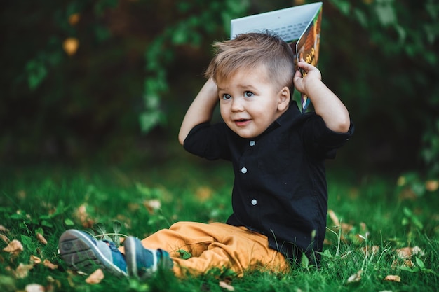 Een kleine jongen leest een boek op het gazon