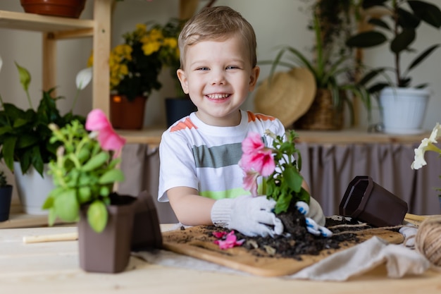 Een kleine jongen met een blondine plant of verplant huisplanten Kleine helper bij klusjes