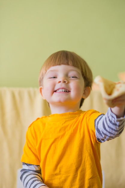 een kleine jongen met een glimlach eet heerlijke pannenkoeken met jam